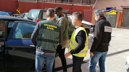 Agentes de la Guardia Civil y la Gendarmería trasladan a uno de los detenidos.