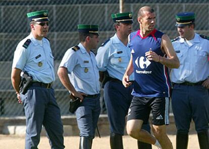 Zidane corretea por la banda junto a unos policías.