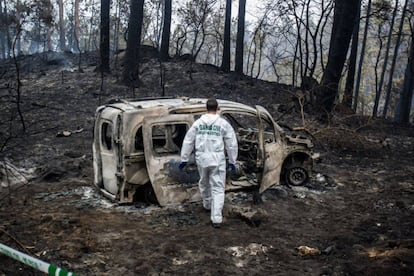 Agentes examinan una furgoneta calcinada durante la pasada ola de incendios. 