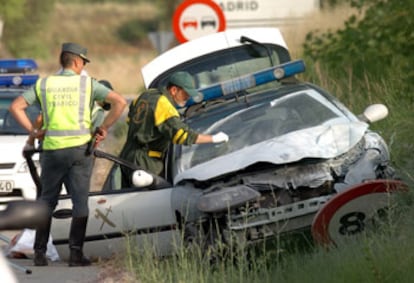 Compañeros de los agentes asesinados examinan el vehículo en el que viajaban tras el tiroteo.