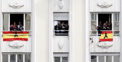 Un grupo de personas miran desde las ventanas de un edificio el paso del cortejo fúnebre del presidente, Adolfo Suárez, a su salida del Congreso de los Diputados.