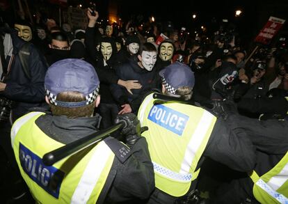 Los agentes de policía se enfrentan a los manifestantes enmascarados de Londres, este jueves noche.