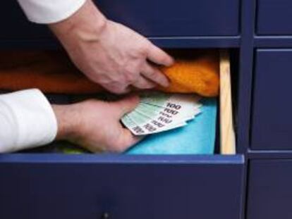 Una persona guarda dinero en un cajón.