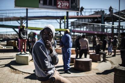 Un hombre observa mientras jóvenes se reúnen en la estación de tren Kliptown, República de Sudáfrica.