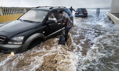 Varios vecinos intentan retirar sus vehículos por la subida de la marea en Dénia (Alicante).
