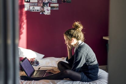 Adolescente con un portátil en su dormitorio.