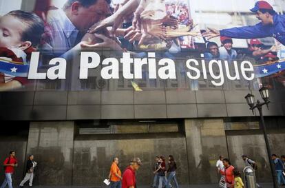 Ciudadanos de Caracas caminan este miércoles frente a un cartel que retrata a Chávez y Maduro cerca de la Asamblea Nacional.