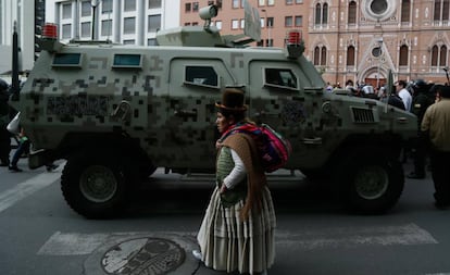 Una mujer camina frente a una tanqueta en el centro de La Paz.