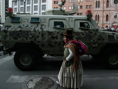 Una mujer camina frente a una tanqueta en el centro de La Paz.