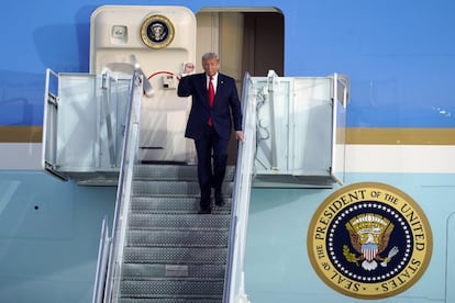 Trump alza el brazo mientras desciende del avión presidencial en el aeropuerto de Sanford, en Florida.