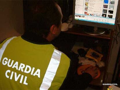 Un investigador de la Guardia Civil registra el ordenador de uno de los detenidos en Sevilla.