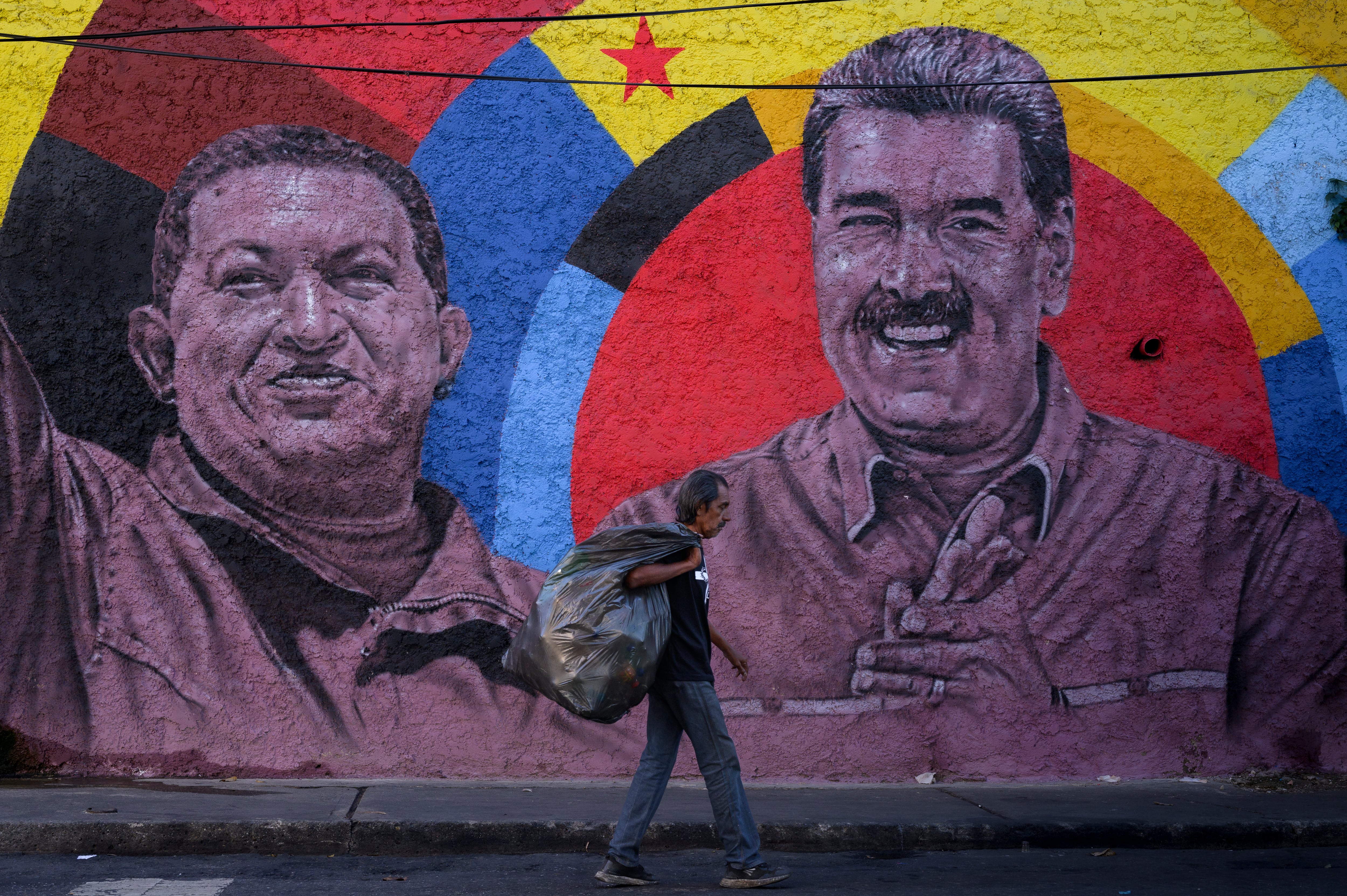 Una persona pasa frente a un mural de Nicolás Maduro y Hugo Chávez, en Caracas.