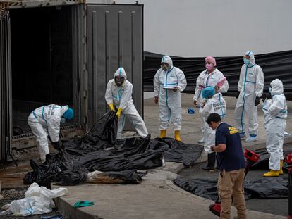 Agentes de criminalística trabajan con los cadáveres acumulados en los contenedores de la morgue de Guayaquil, el 12 de junio.