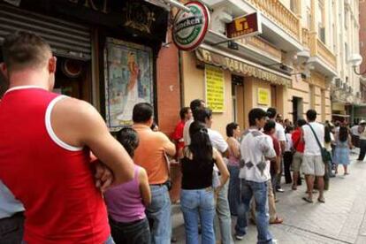 En la foto, una multitud de inmigrantes hacen cola ante una oficina de la Seguridad Social en Madrid.