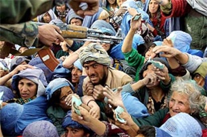 Un soldado de la Alianza trata de controlar a una masa de kabulíes desesperados por conseguir su saco de comida.