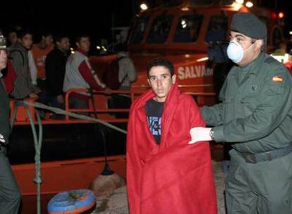 Un agente de la Guardia Civil acompaña a uno de los inmigrantes que navegaban en una patera localizada ayer en aguas de Motril.