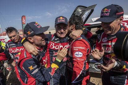 Carlos Sainz, es felicitado por Stephane Peterhansel, izquierda y Nasser Al-Attiyah al final de la etapa doce del Rally Dakar.