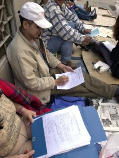 Inmigrantes rellenan sus papeles para entregarlos en una oficina de la Delegación del Gobierno de Madrid.