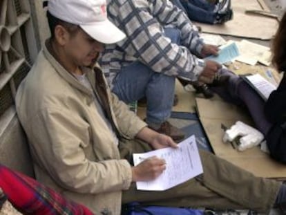 Inmigrantes rellenan sus papeles para entregarlos en una oficina de la Delegación del Gobierno de Madrid.