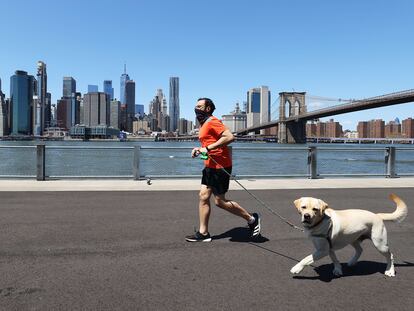 Un hombre corre con su perro en Brooklyn, Nueva York.