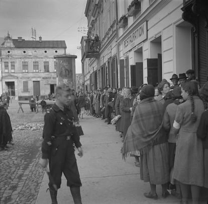 Jewish citizens of Oświęcim form a line, under the supervision of a German soldier.