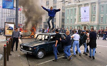Un aficionado salta sobre uno de los coches destrozados en las calles de Moscú.