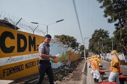 Este penal de Izalco se inauguró para reducir el número de prisioneras de otra cárcel de mujeres, la de Ilopango. No estaba todo construido cuando se abrió. Lo están terminando las propias presas. Por cada día de trabajo, se les condonan dos días de cárcel. En la imagen, un grupo de presas con carretillas y pintando el muro exterior ante la mirada de uno de los guardias.