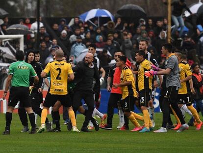 Los jugadores de Comunicaciones increpan a Freire, encapuchado.