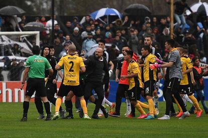 Los jugadores de Comunicaciones increpan a Freire, encapuchado.