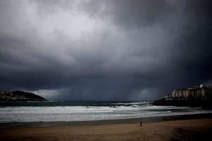 Un hombre pasea a su perro por la playa del Orzán en A Coruña, este viernes. La Xunta ha activado para hoy viernes la alerta naranja por temporal costero en las provincias de A Coruña y Lugo, donde se esperan olas de seis metros, mientras que Protección Civil ha alertado de fuertes vientos de hasta 100 kilómetros por hora como consecuencia del paso de la borrasca Álex.