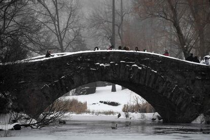 Varias personas caminan por un puente cubierto de nieve en Central Park, Nueva York.