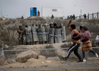 Dos manifestantes pasan delante de agentes de policía en Arequipa, este jueves. 