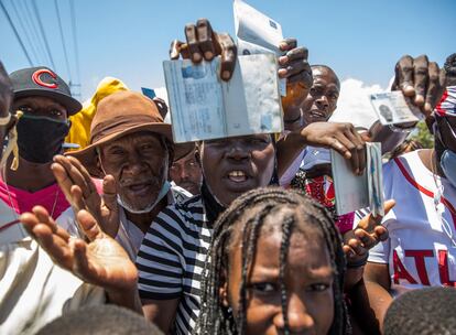 Cidadãos haitianos mostram seus passaportes para pedir asilo em frente à embaixada dos Estados Unidos em Tabarre, neste sábado.