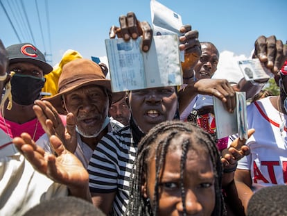 Ciudadanos haitianos muestran sus pasaportes para pedir asilo frente a la embajada de Estados Unidos en Tabarre, este sábado.