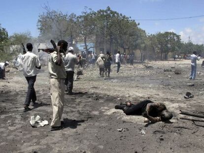 Un soldado somalí mira el cuerpo quemado de una de las víctimas del atentado en el centro de Mogadiscio.