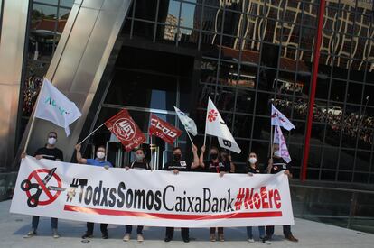 Varias personas con una pancarta en la que se lee: "Todos Somos Caixabank, no ERE", durante una concentración contra los despidos en la entidad, en las Torres Kio de Plaza de Castilla de Madrid, el 20 de mayo.