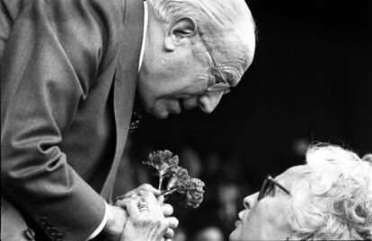 Enrique Tierno Galván,recibe un ramo de claveles de manos de una mujer, en la tribuna del Santiago Bernabéu durante el partido Real Madrid-Barcelona, en marzo de 1981.