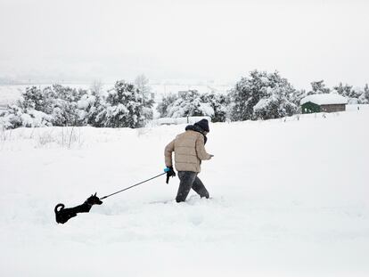 En la imagen, un joven con su perro pasea en la nieve en Barracas (Castellón).
