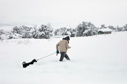 En la imagen, un joven con su perro pasea en la nieve en Barracas (Castellón).