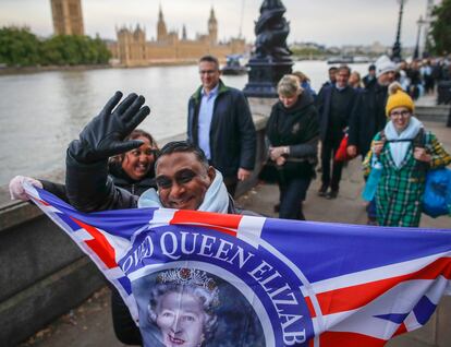 Un hombre sostiene una bandera con la imagen de la reina Isabel II frente mientras hace cola para despedirse de la monarca, este domingo en Londres.