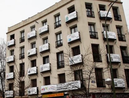 Vista del edificio en el que el estilista Alejandro Biehler ha colgado carteles con los objetos que subasta por eBay para pagarse un viaje a Cádiz. El inmueble se encuentra frente a la Puerta de Toledo, en Madrid.