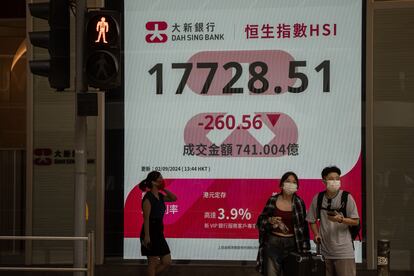 Unas personas pasan junto a un cartel que muestra el Índice Hang Seng en Hong Kong, China, el 2 de septiembre de 2024