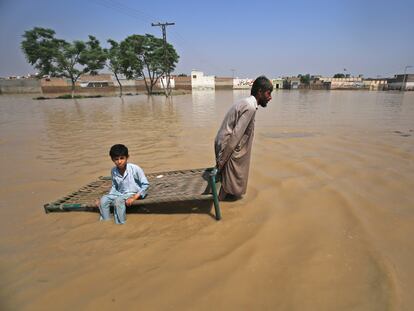 Dos personas en mitad de la zona inundada a finales de agosto por las fuertes lluvias en Pakistán.