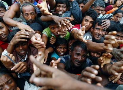 Refugiados Rohingya estiran sus brazos para alcanzar la ayuda distribuida por una organización local en un campamento de Cox's Bazar (Bangladés). 
