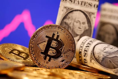 FILE PHOTO: A representation of virtual currency Bitcoin and U.S. One Dollar banknotes are seen in front of a stock graph in this illustration