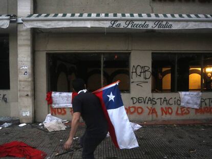 Un manifestante camina frente a un restaurante cerrado en Santiago de Chile.