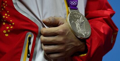 La medalla de plata del chino Lu Haojie, mientras posa en el podio tras la final de halterofilia masculina -77kg.