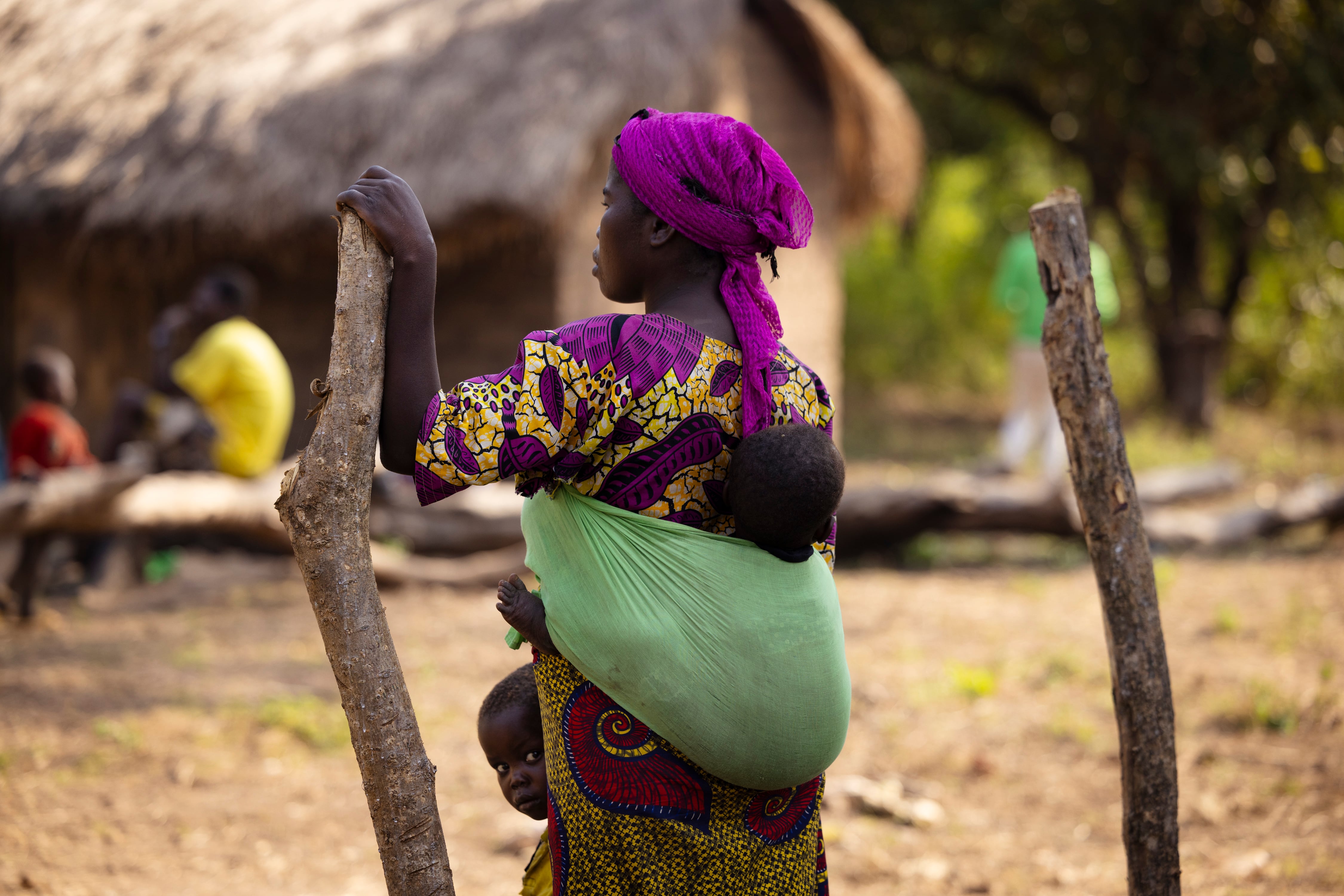 Una madre con sus hijos en la aldea de Kpodikalam, donde Unicef acaba de inaugurar una nueva escuela, en noviembre de 2025.