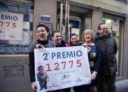 La propietaria de la administración de lotería nº3 de la calle Cerrajeros de Granada, junto a un grupo de vecinos muestran una ampliación del número 12775, segundo premio.