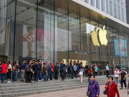 Una fila de clientes guarda turno frente a una tienda de Apple.